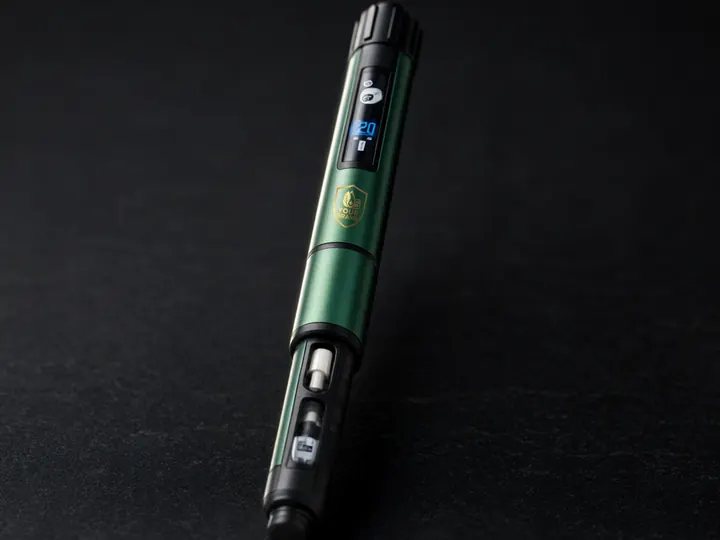 Green premium clinic pen on black stone, its digital dose window lit blue and the YOUR BRAND shield on the barrel