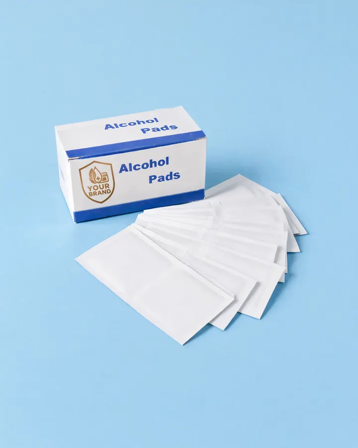 Box of YOUR BRAND alcohol pads with loose pads fanned out in front of it, on a light blue background