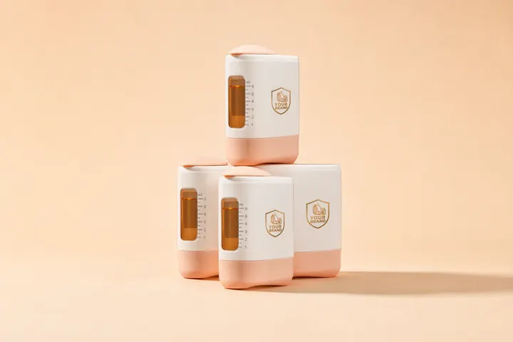 Four refillable scalp applicators stacked on peach, white bodies with peach bases, amber 6 mL windows and a gold YOUR BRAND shield on each
